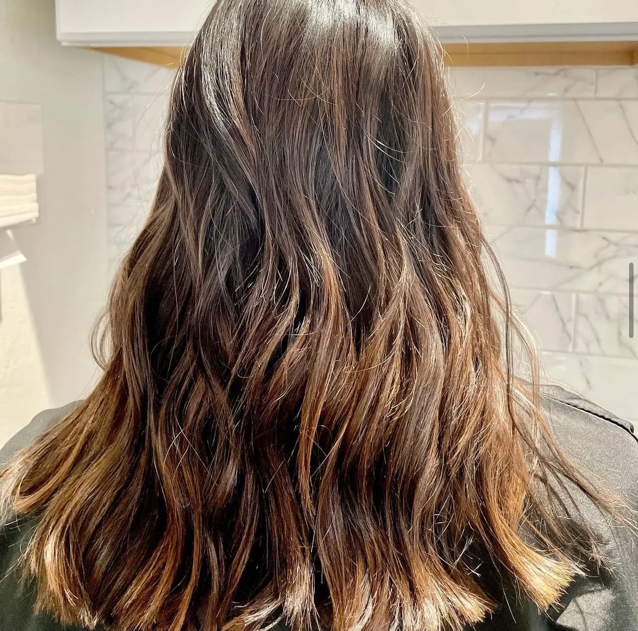 Brunette hair with warm caramel ribbons and curled ends